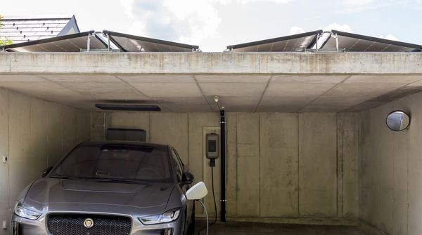 Ein silbernes Elektroauto lädt an einer Ladestation zuhause.